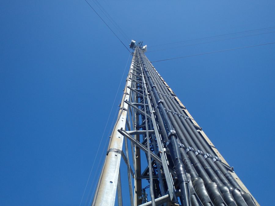 Coax cable runs climbing a tower into a clear blue sky
