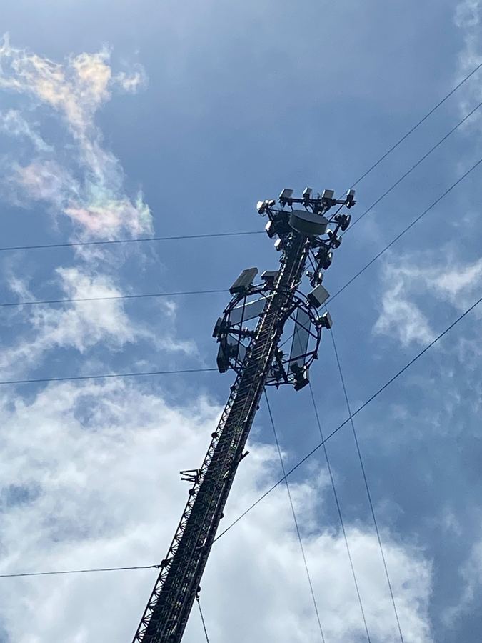 Tower top with antennas against clouds and blue sky